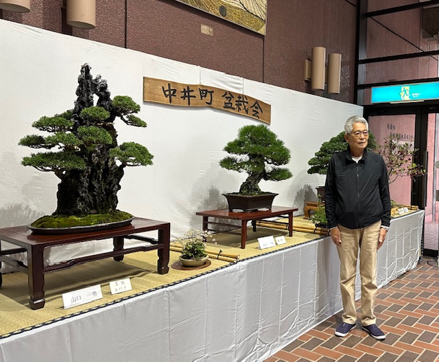 盆栽の前に立つ山口一男さんの写真