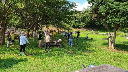厳島湿生公園内の木陰の下で大人と子どもが一緒にラジオ体操を行っているところ