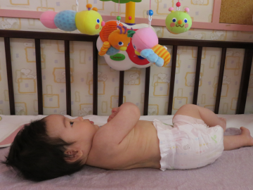紙おむつをはいてベッドの上にいる赤ちゃんの写真