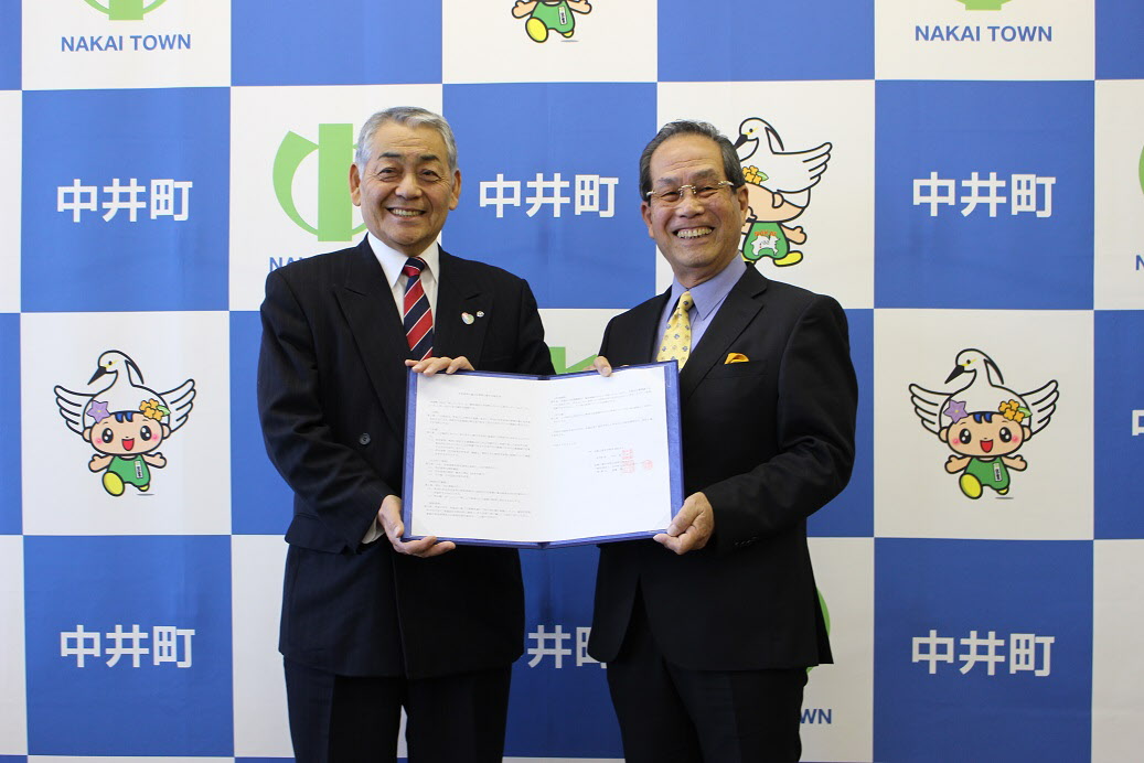 2人の男性が笑顔で1つの協定書を持っている写真