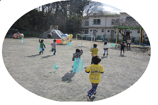 遊具がある広場で子どもたちが凧揚げをしている写真