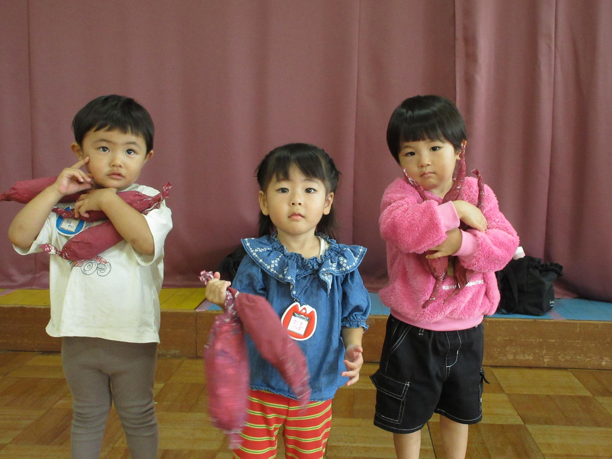 3人のこどもがおもちゃのお芋をいっぱい抱えて嬉しそうな様子