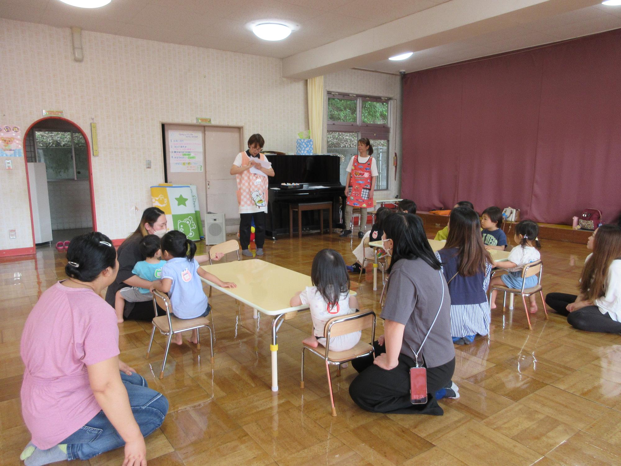 未就園児と保護者が参加するなかよしクラブで、指導者から話を聞く大勢の親子の様子