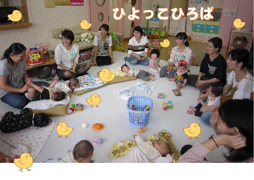 お母さんと赤ちゃんが円になって座り、中央にバスケットに入ったおもちゃがある、ひよっこひろばの室内の写真