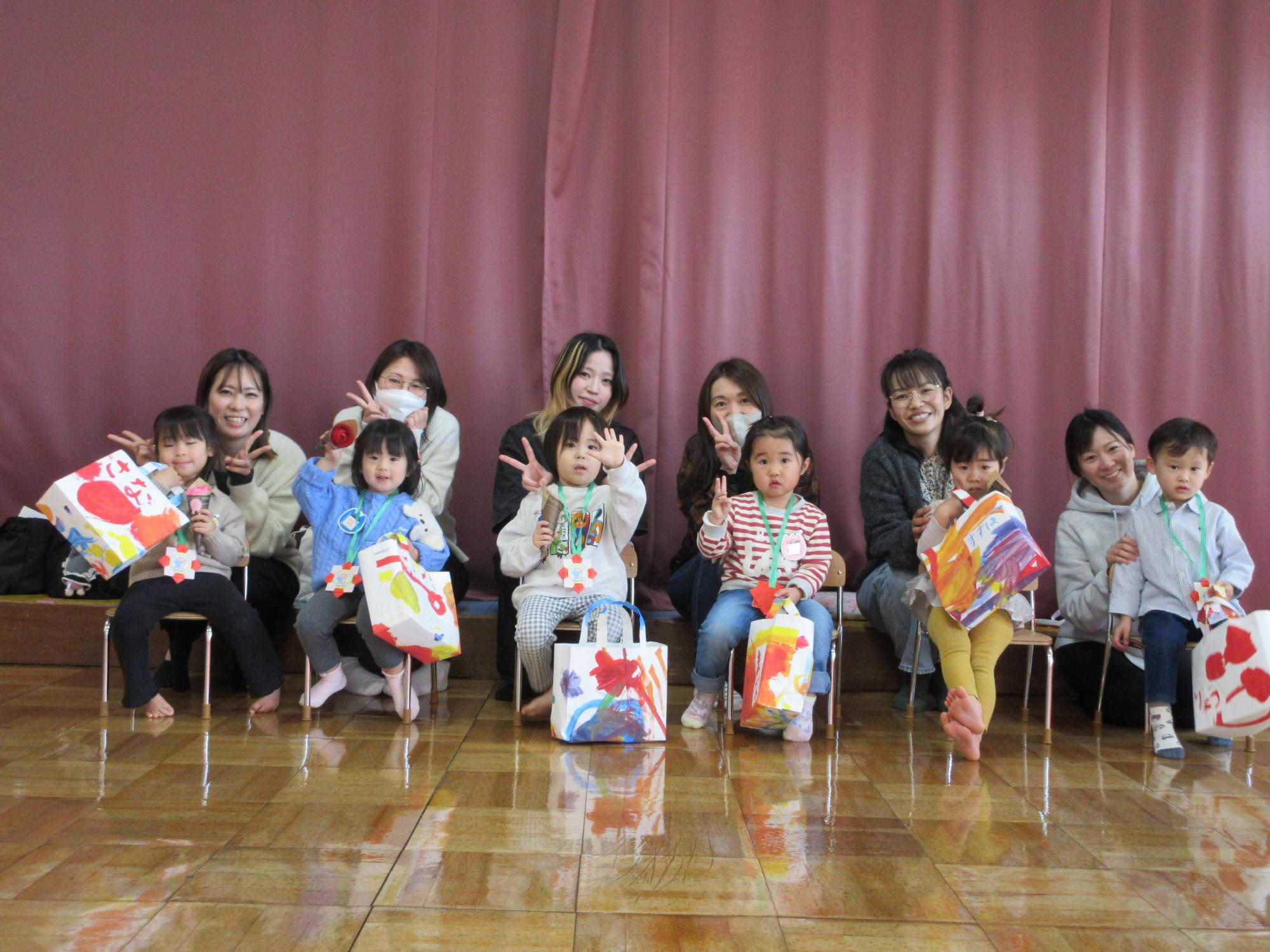 6組の親子がなかよしクラブで制作したバックをお披露目している様子