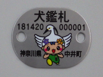 金属製でキャラクターが印刷されている犬鑑札の写真 6桁の数字2組と「神奈川県 中井町」と書かれている。