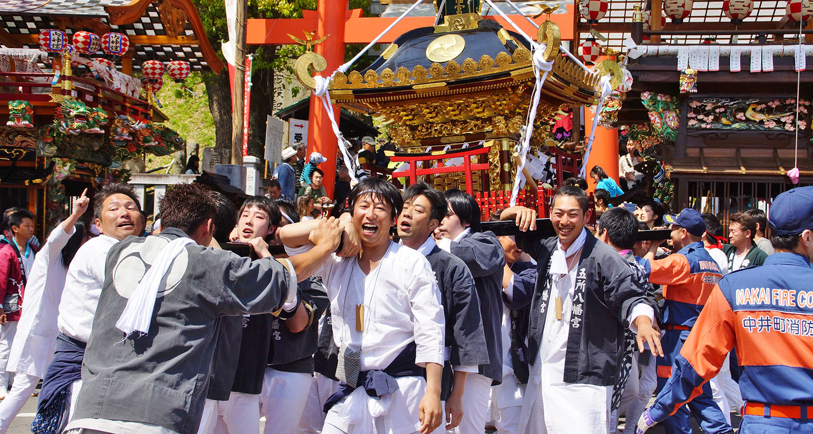 笑顔で神輿を担ぐ人々の写真