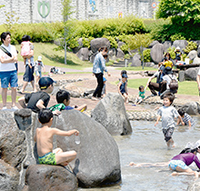 晴れの日に公園で水遊びを楽しむ親子たちの写真