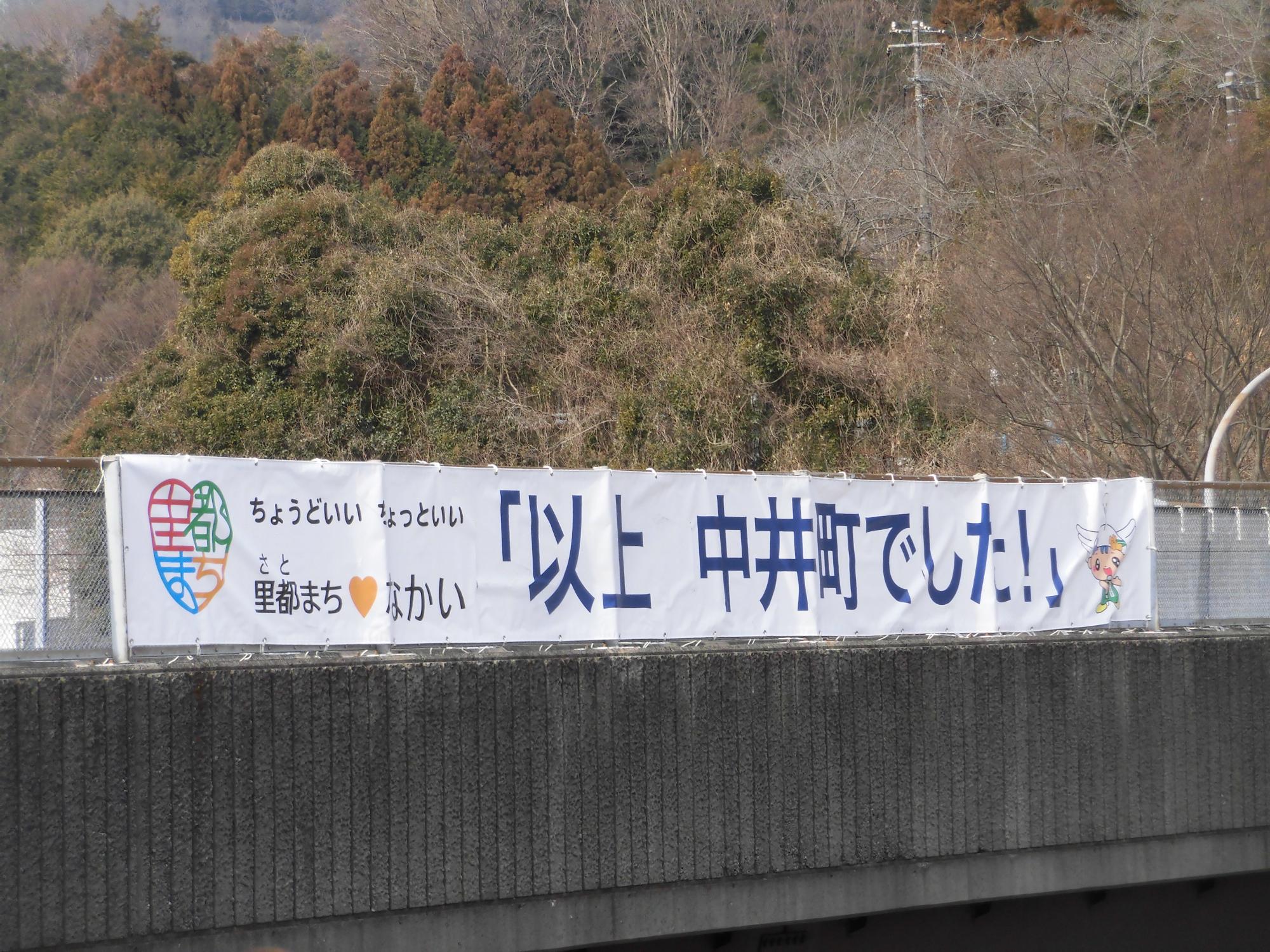 「以上　中井町でした」と書かれている東名高速道路上に設置された横断幕